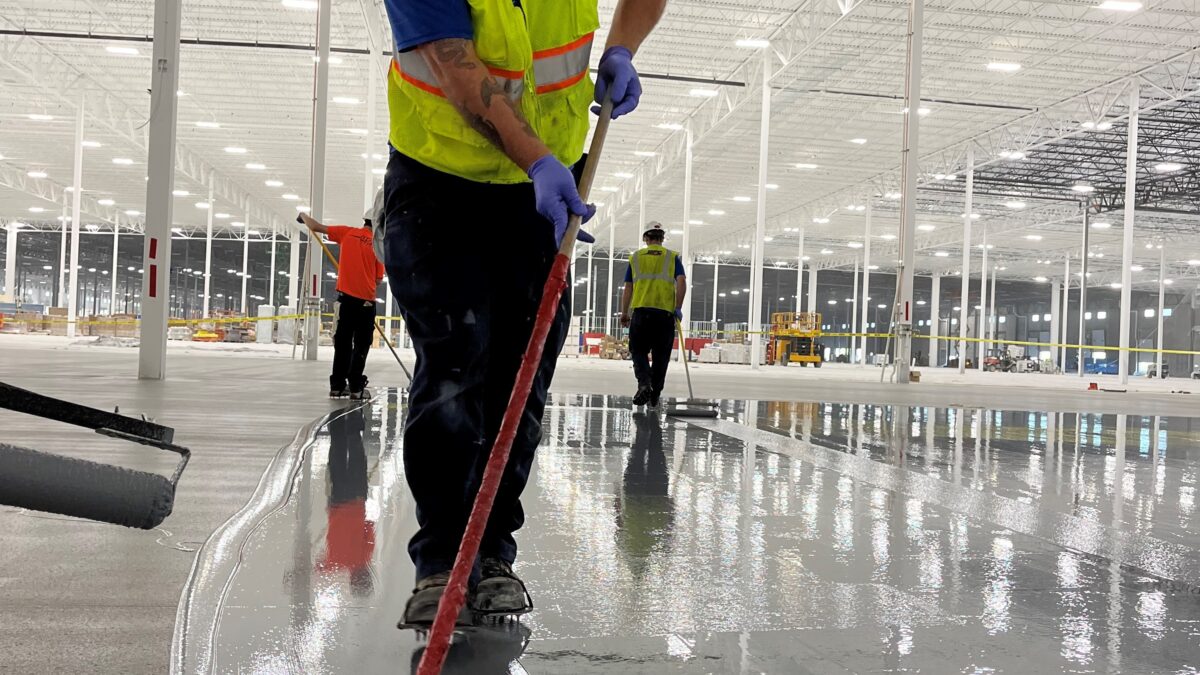 Crew installing epoxy floor coating in large warehouse serving Michigan, Ohio and Indiana