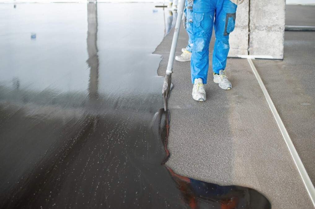 A Michigan Specialty Coatings worker spreading epoxy on the ground in a warehouse in St. Clair, MI