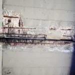 A wall with peeling paint, revealing decaying concrete in Michigan & Ohio
