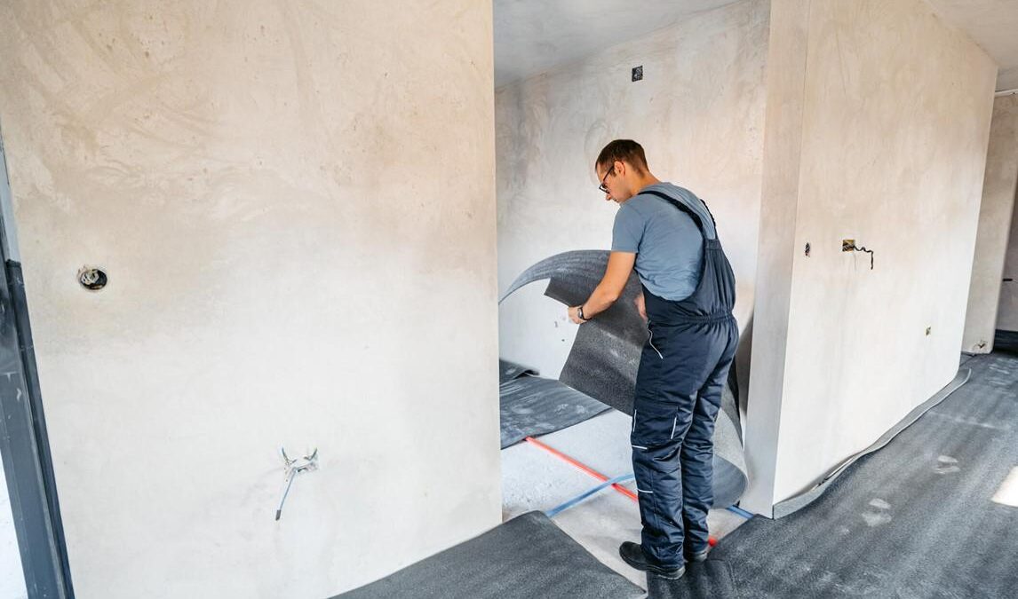 A Technician in overalls installs new flooring in a home in Saint Clair, MI